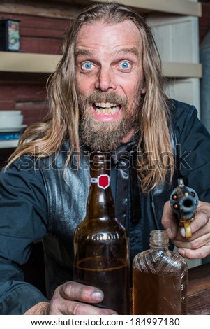 Crazed Western Man Aims Gun Towards You as he Sits at Table - stock photo - stock-photo-crazed-western-man-aims-gun-towards-you-as-he-sits-at-table-184997180