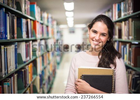 In the library - pretty female student with books working in a high school library. - stock photo
