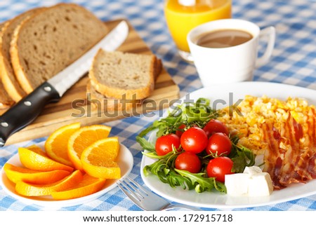 stock-photo-closeup-of-a-breakfast-table-with-bacon-scrambled-eggs-fruit-and-orange-juice-172915718.jpg