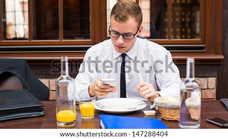  - stock-photo-smiling-attractive-businessman-sitting-with-smartphone-in-restaurant-147288404