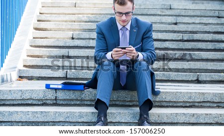  - stock-photo-businessman-using-laptop-pc-and-mobile-phone-he-is-sitting-on-a-stairs-157006250