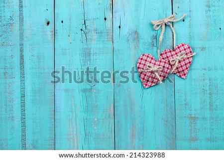 Two plaid red hearts hanging from rope on antique teal blue distressed ...