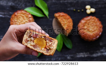 Close up of Vietnamese sweet food from top view, woman hand take moon cake for mid autumn festival when full moon, delicious homemade mooncake of Vietnam cuisine culture