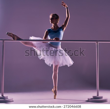 stock-photo-classic-ballet-dancer-in-white-tutu-posing-on-one-leg-at-ballet-barre-on-a-lilac-background-272046608.jpg