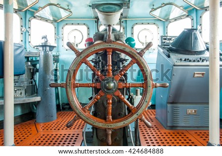 stock-photo-wooden-steering-wheel-in-ship-control-cabin-room-424684888.jpg