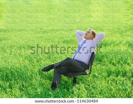  businessman relaxing on a chair on a green meadow - stock photo