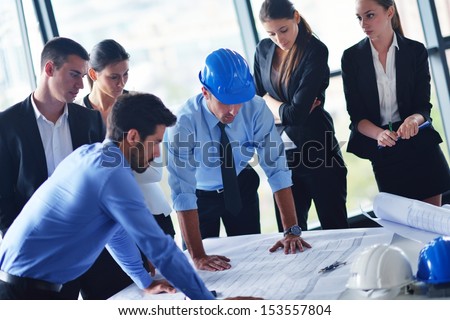 business people group on meeting and presentation  in bright modern office with construction engineer architect and worker looking building model and blueprint planbleprint plans - stock photo