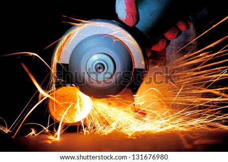 Worker cutting metal with grinder. Sparks while grinding iron - stock photo