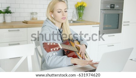 http://thumb1.shutterstock.com/display_pic_with_logo/61004/631974620/stock-photo-young-wonderful-female-sitting-at-table-and-using-laptop-with-headphones-while-playing-guitar-in-631974620.jpg