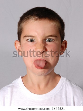 Young Boy In White Shirt With Tongue Sticking Out Angrily - Stock Photo