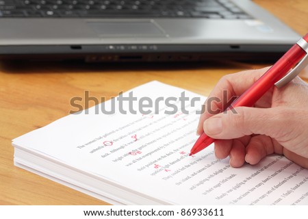 Hand with Pen Proofreading a Manuscript - undiscernable text so can be any Language - stock photo