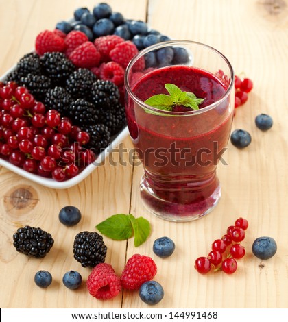 A glass of berry smoothie with fresh fruits, shallow depth of field - stock photo