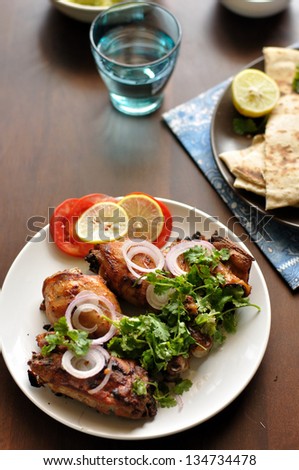 ... Chicken Legs served on top of a naan bread with salad - stock photo