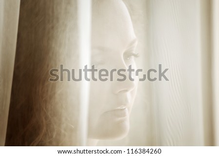 Sad beautiful woman looking out the window - stock photo