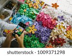 Small photo of People use smartphone talking picture of colorful artificial Flowers from mulberry paper.