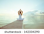 Caucasian woman practicing yoga at seashore - stock photo