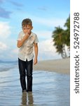 Small photo of Full growth portrait on a tropical beach: slim and handsome 8 years old boy in wet clothes without shoos ankle-deep in water. He pondered and I put a hand to face