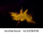 Small photo of Bizarre forms of golden glitter powder paint explode in front of a black background to give off fantastic colors and forms.