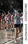 Small photo of Bucharest / Romania - 07/26/2014: Water fight event, people having fun and cooling by throwing water from bottles. Wet clothes, wet hair, all wet, blur green background and water drops.
