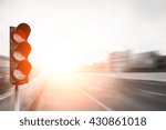 Small photo of Red traffic light on the expressway asphalt road with car in a city landscape at sunrise. light sign for car stop and speed reduction. Dangerous,warning signal,semaphore driving. Driving on a Highway.