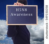 Small photo of A women holding a chalk board with word " H5N8 AWARENESS " isolated in a background of blue sky. H5N8 is a subtype of the Influenza A virus.