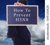 Small photo of A women holding a chalk board with word " HOW TO PREVENT H5N8 " isolated in a background of blue sky. H5N8 is a subtype of the Influenza A virus.