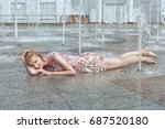 Small photo of Woman lies in a city fountain and flirts, she is all wet and happy.