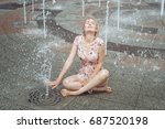 Small photo of Woman sits in a fountain, she is all wet.