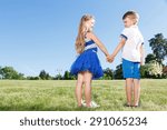 Small photo of Love with first glance. Pleasant little children holding their hands together and looking at each other while standing backwards.