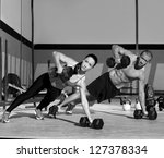 Gym man and woman push-up strength pushup with dumbbell in a workout - stock photo