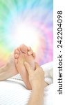 Small photo of Reflexology working the Solar Plexus - Reflexologist holding a client's foot while applying pressure to the solar plexus area on a rainbow colored spiraling energy formation background