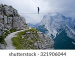 Small photo of MONTE PIANA, DOLOMITES/ITALY - SEPTEMBER 08, 2013: an acrobat on a rope tended above an abyss during "Highline Meeting" of tightrope walkers from around the world taking place every year on september