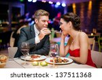 Affectionate couple in restaurant, him feeding she - stock photo