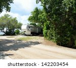 stock-photo-fifth-wheel-camper-parked-at-a-camping-site-along-the-river-s-edge-at-florida-142203454.jpg