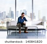 Attractive casual business man working in a Penthouse Suite with Los Angeles Skyline behind him - stock photo