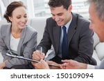 Businessman signing contract while his partner is looking at him in cosy meeting room - stock photo