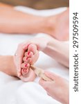 Small photo of Women at reflexology having foot massaged or pressed with wooden stick