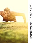 Push ups sport fitness man doing push-ups. Male athlete exercising push up outside in sunny sunshine. Fit shirtless male fitness model in crossfit exercise outdoors. Healthy lifestyle concept. - stock photo
