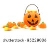 Halloween pumpkin and a pile of scattered assorted candies against a white background - stock photo