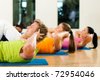 People, man and women, exercising doing sit-ups in gym or fitness club - stock photo