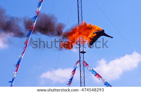 High diver performing a fire dive off a platform above a pool at a circus fair show. Stuntman dressed in black fire protective suite. A very dangerous yet exciting athletic sport stunt.