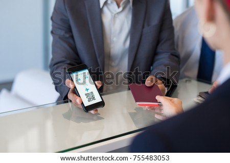 Closeup hand of man showing flight ticket to staff on phone. Hostess checking electronic flight ticket. Airport check in counter and online air ticket.