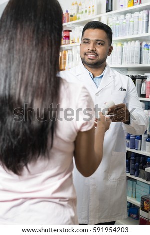 Pharmacist Giving Product To Female Customer In Pharmacy