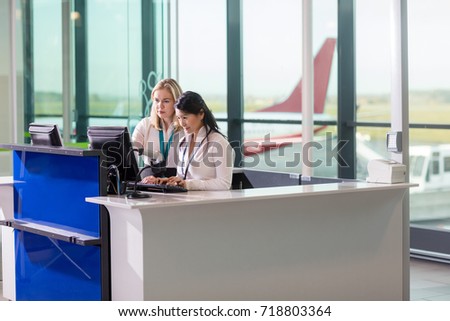 Ground Staff Using Computer At Counter In Airport