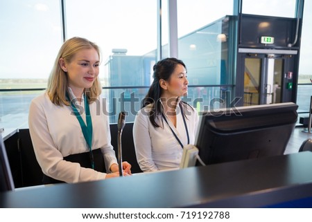Receptionists Sitting At Help Desk In Airport
