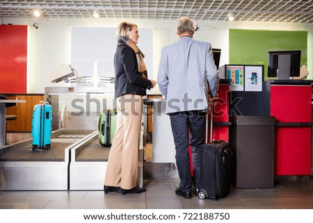 Senior Business Couple Standing At Airport Check-in Desk