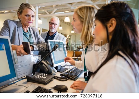 Staff Talking With Businesswoman At Airport Check-in