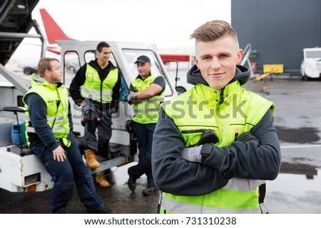 Worker With Arms Crossed Standing While Colleagues Communicating