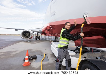 Crew Member Charging Airplane On Runway