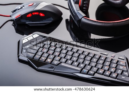 a gaming keyboard, mouse and headset shot over a dark reflective surface